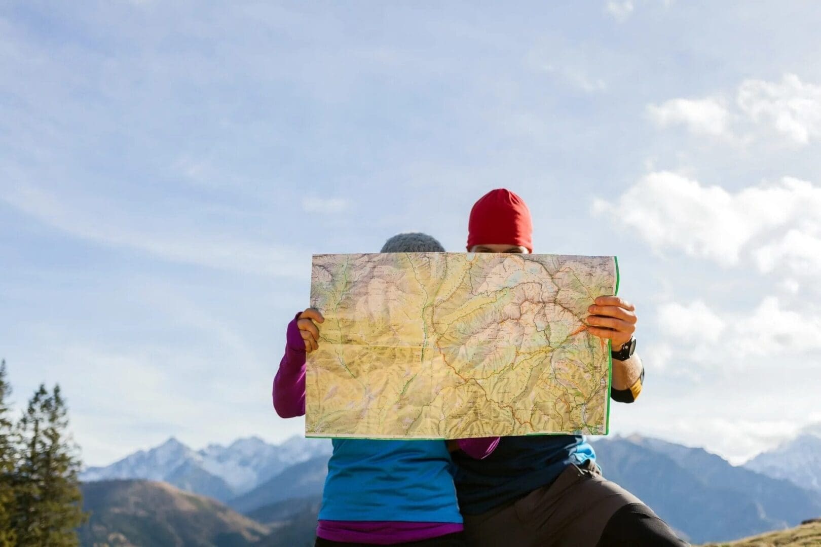Two people holding a map in front of their face.
