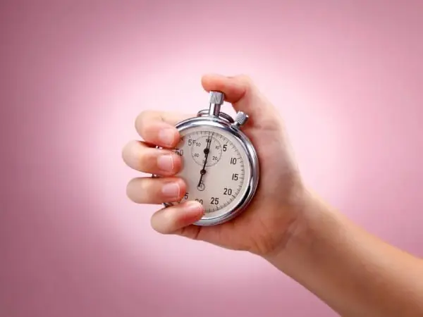 A person holding an analog stopwatch in their hand.